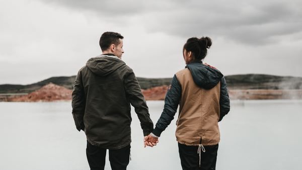 pareja agarrándose de las manos y viendo al agua congelada 